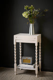 Twisted-leg side table painted in Rococo White, styled with a vase and vintage radio.