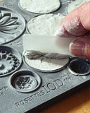 A close-up of the IOD Rosettes 6 x 10 Décor Mould in use, showing detailed designs being carefully removed after casting with air-dry clay. Perfect for DIY and creative projects.