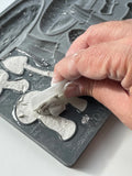 A hand carefully removing a clay casting from the Toadstool IOD Décor Mould, highlighting the intricate mushroom details for creative projects and crafts.