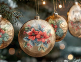 Gold Christmas baubles decorated with IOD Yuletide Decor Transfers, showcasing vintage-style poinsettia and holly designs, hanging from a tree with festive lights.